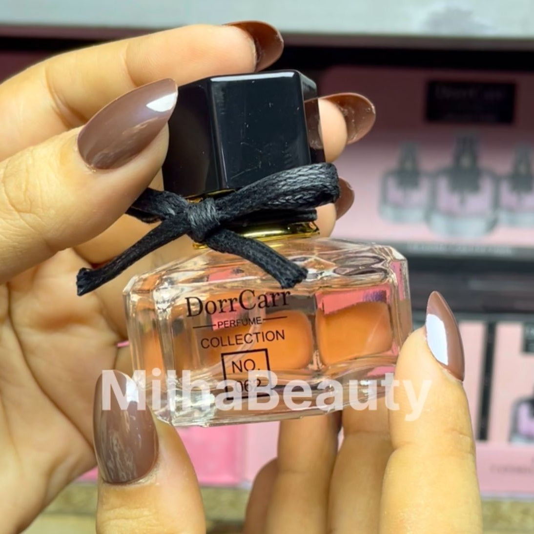 Hand holding a small perfume bottle labeled 'Dorr Carr' with a blurred background.