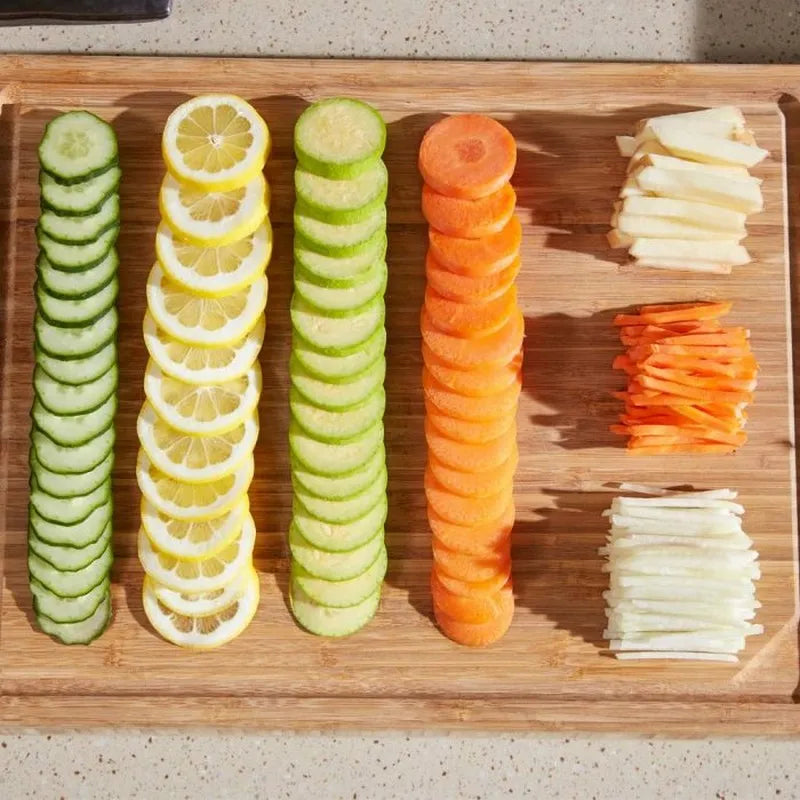 Sliced vegetables including cucumbers, lemons, carrots, and radishes on a wooden cutting board.