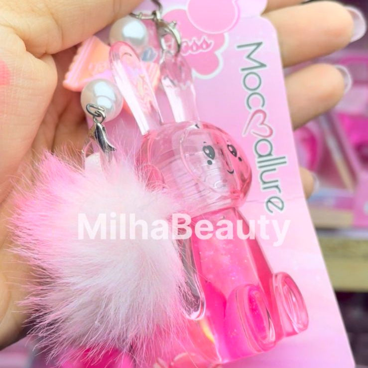 Pink hair tie with decorative elements held by a hand, with a visible brand name.