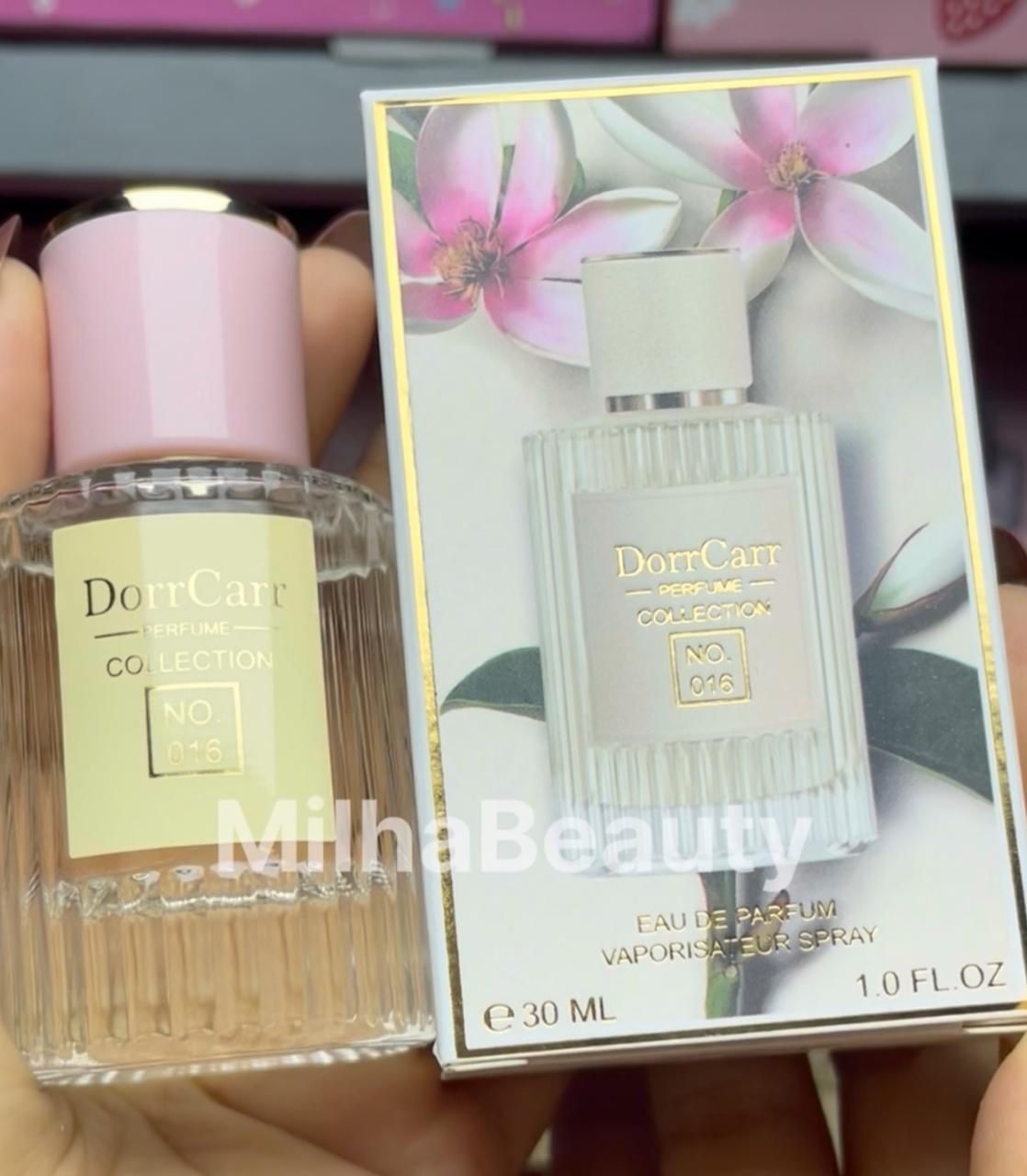 Perfume bottle and packaging with floral design held by a hand