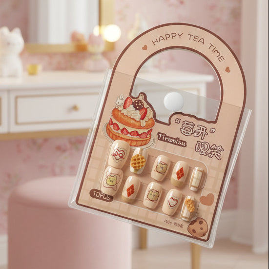 A package of decorative false fingernails resting on a black laptop keyboard. The nails are displayed in a pink arched card holder with illustrations of cakes and tea-themed graphics