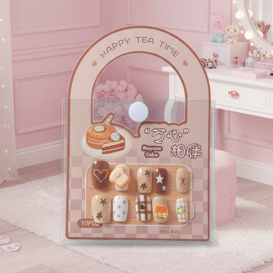 A set of 10 cute tea-themed false press-on nails in a clear plastic blister pack with a beige arch card that reads 'Happy Tea Time' and shows cake illustrations. The nails feature designs like hearts, stars, stripes, and small desserts.