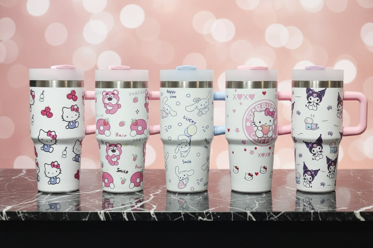 Five Hello Kitty themed travel tumblers with different character designs, displayed side-by-side on a dark marble surface against a pink bokeh background.
