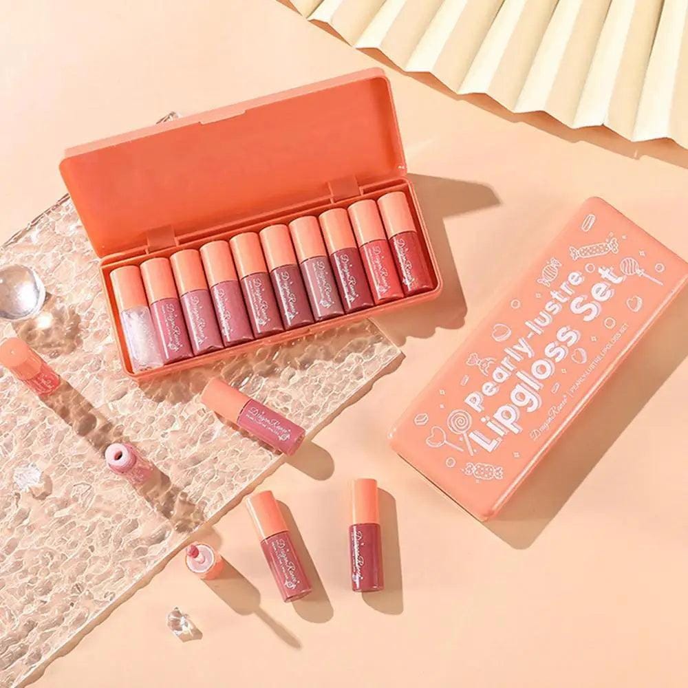 Set of lip glosses in an open box on a textured surface with a decorative background.