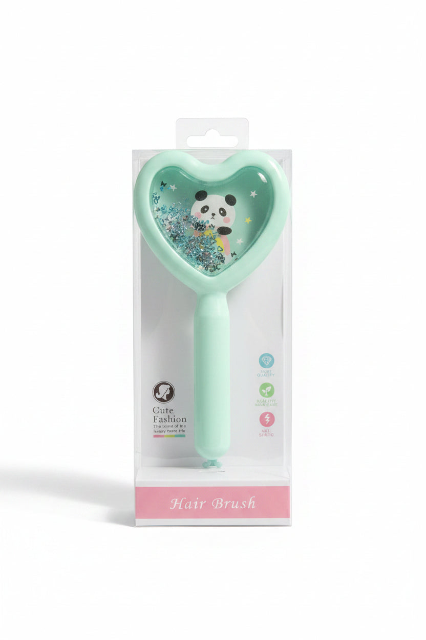 A mint green heart-shaped hair brush with a panda and glitter insert, shown inside its clear retail packaging box. The box is placed on a colorful, patterned fabric background.