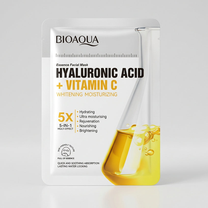 A packaged facial mask sheet labeled 'HYALURONIC ACID + VITAMIN C' by Bio Aqua, photographed in a casual indoor setting with a keyboard and monitor visible in the background.