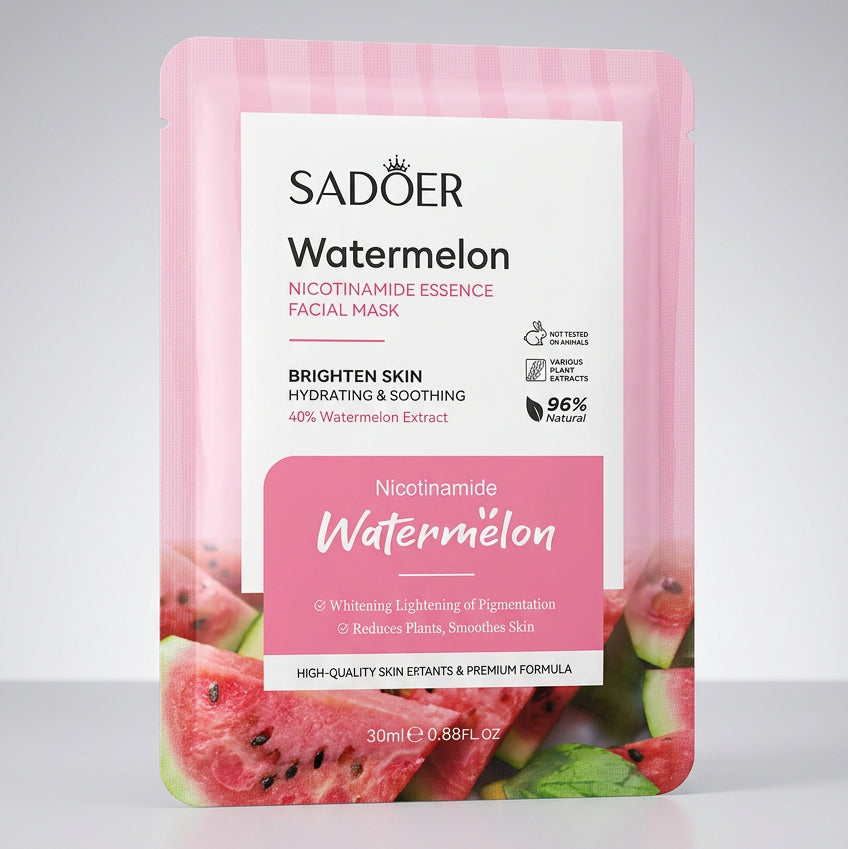 A pink Satoer Watermelon facial mask pouch resting on a dark surface with a hand pointing at the front label. A laptop keyboard and monitor are visible in the background.