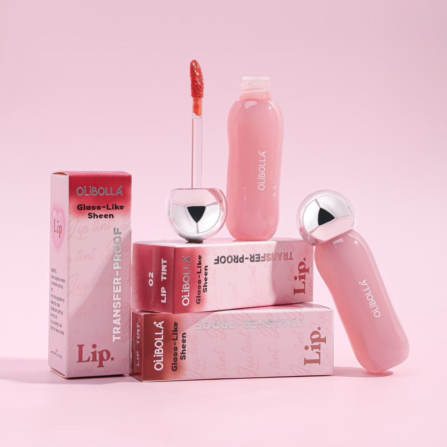 Pink lip gloss set with applicator and packaging on a pink background
