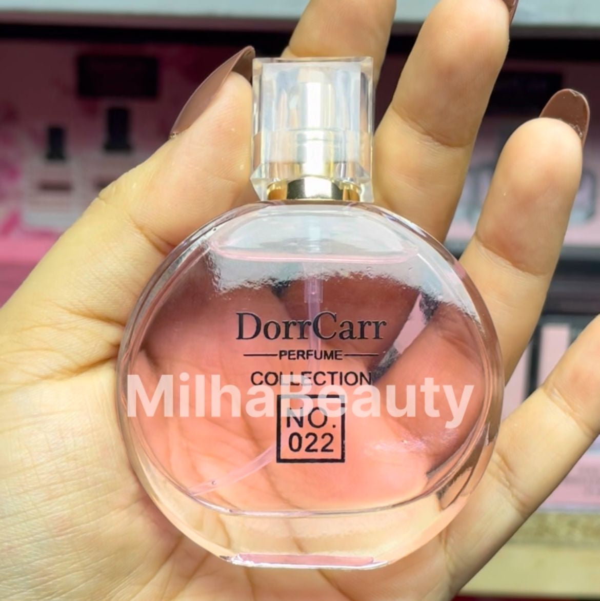 Hand holding a perfume bottle labeled 'Dorr Carr' with a blurred  background.