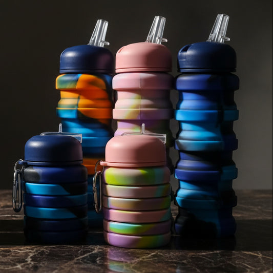 Colorful collapsible water bottles with silicone sleeves on a textured surface.