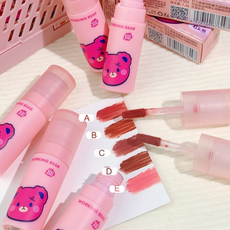 Pink lip gloss tubes and applicators from Working Bear arranged on a light surface, with five color swatches labeled A through E showing different shades of pink and brown lip color.