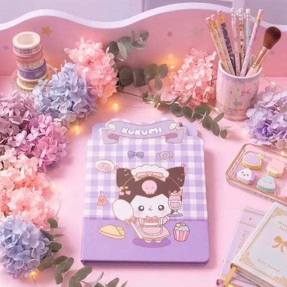 A pastel pink desk setup featuring a Kuromi-themed purple and white gingham notebook or planner cover as the central product, surrounded by decorative flowers, pencils, a small tray, and a matching pink chair in a styled room scene.