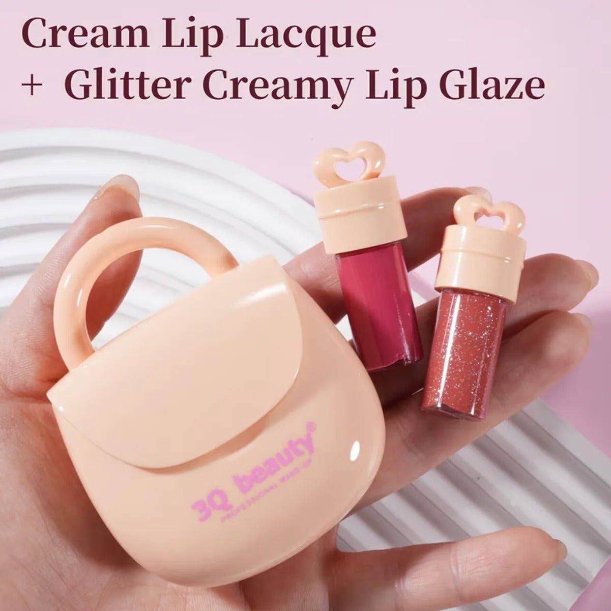 Hand holding a small pink case with two lip products labeled 'Cream Lip Lacque' and 'Glitter Creamy Lip Glaze' by 3Q Beauty.