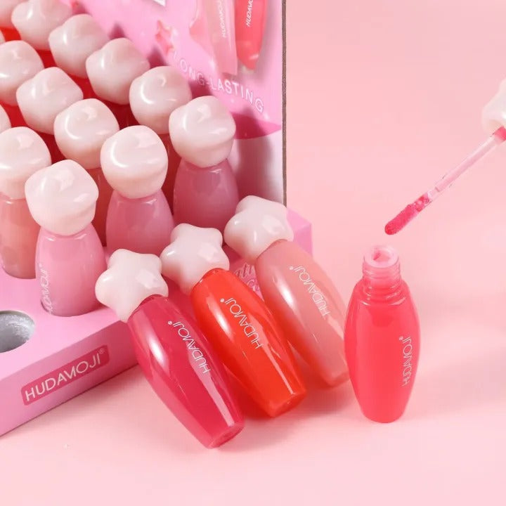 Set of lip glosses with a pink background, featuring the brand 'HUDAMOJI'.