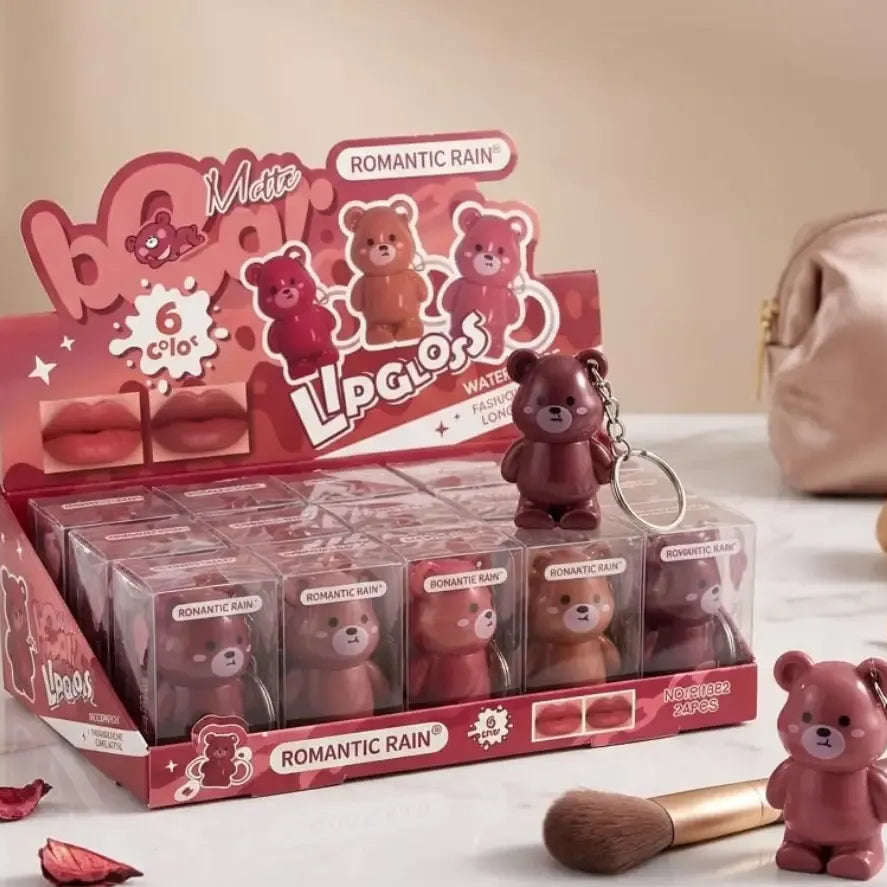 A retail display box of lip glosses under the brand 'Lipgloss' and sub-brand 'Romantic Rain' in 'Matte' finish. The packaging features cute teddy bear illustrations and displays six different shades of matte lip gloss.