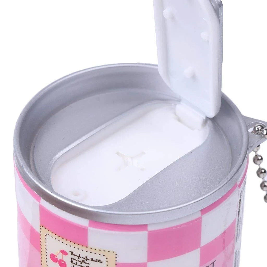 A close-up of a novelty can-shaped container with a pink and white checkered pattern, a silver metal rim, and a hinged white lid that is open, showing a white interior. A small decorative label is visible on the front.