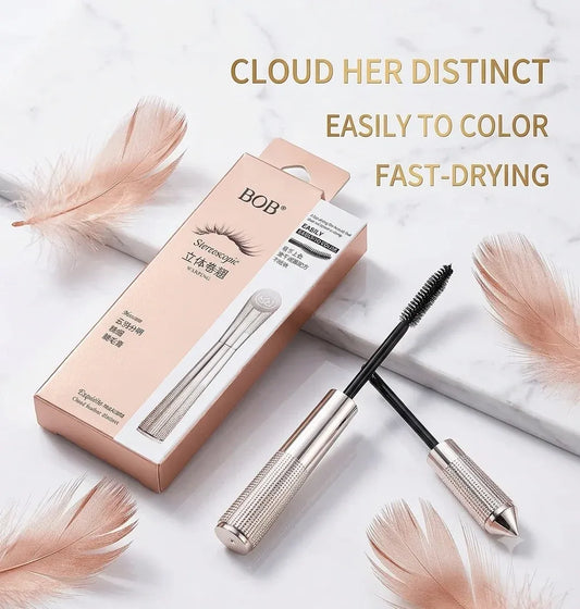 BOB+ Eyelash Mascara shown with its retail box, applicator wand, and spoolie on a white marble surface with decorative feathers. Text on the image reads: 'CLOUD HER DISTINCT EASILY TO COLOR FAST-DRYING'.