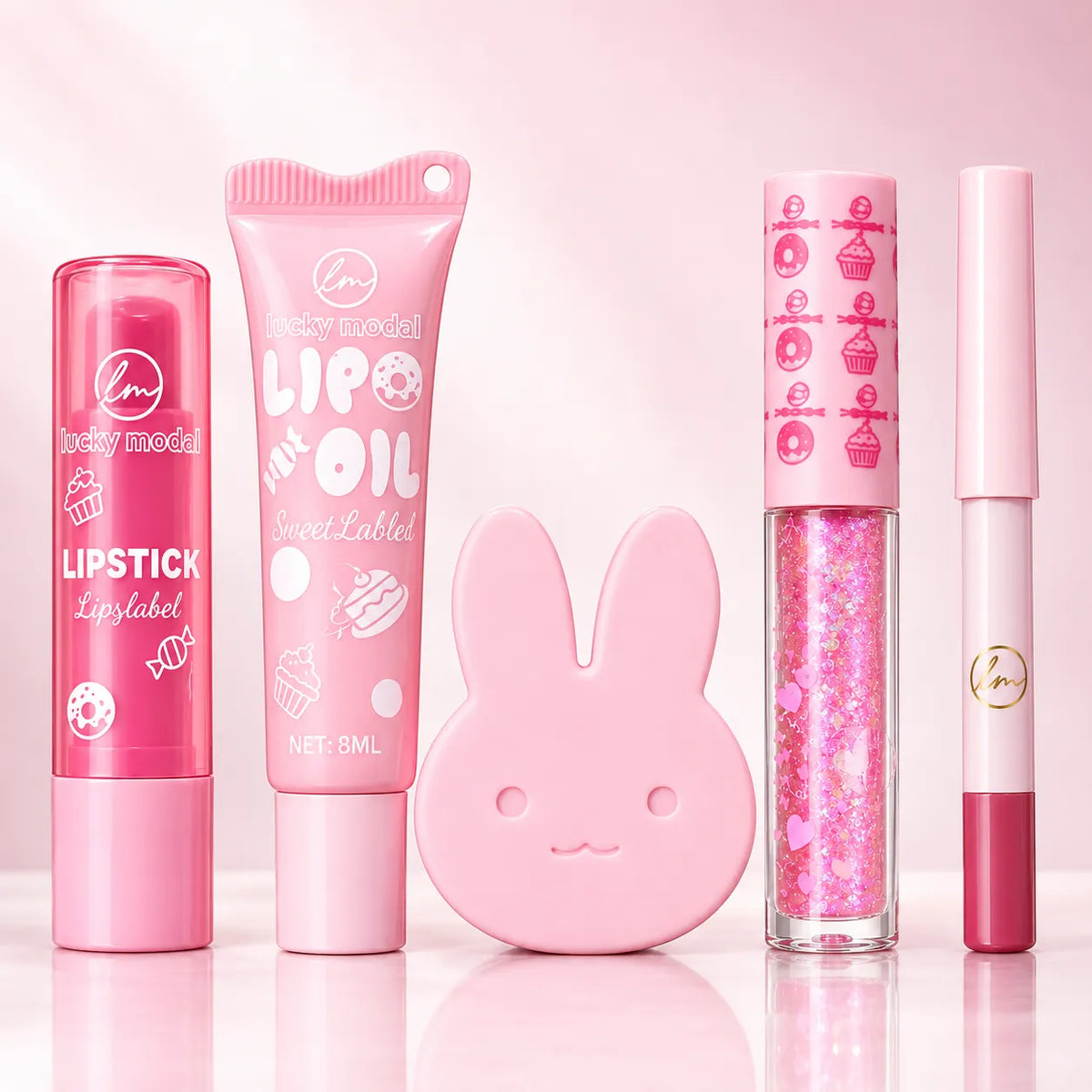Four pink lip products arranged on a glossy pink surface against a soft pink background: a lip balm tube, a lip oil tube, a glitter lip gloss tube with a bunny-shaped cap, and a lip liner tube. The products are branded 'lucky model'.