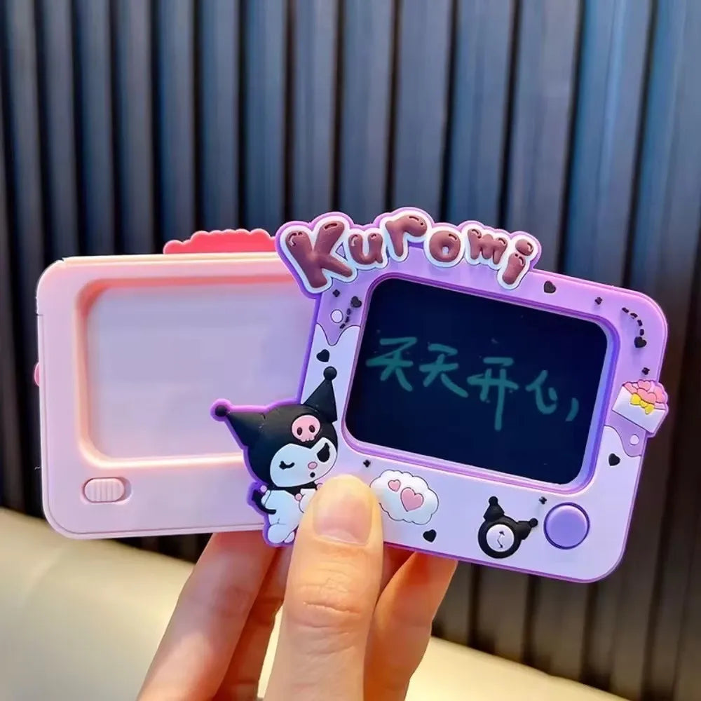 A hand holds a Kuromi-themed electronic drawing tablet. The device has a pastel purple and pink body with a black screen showing green Chinese characters.