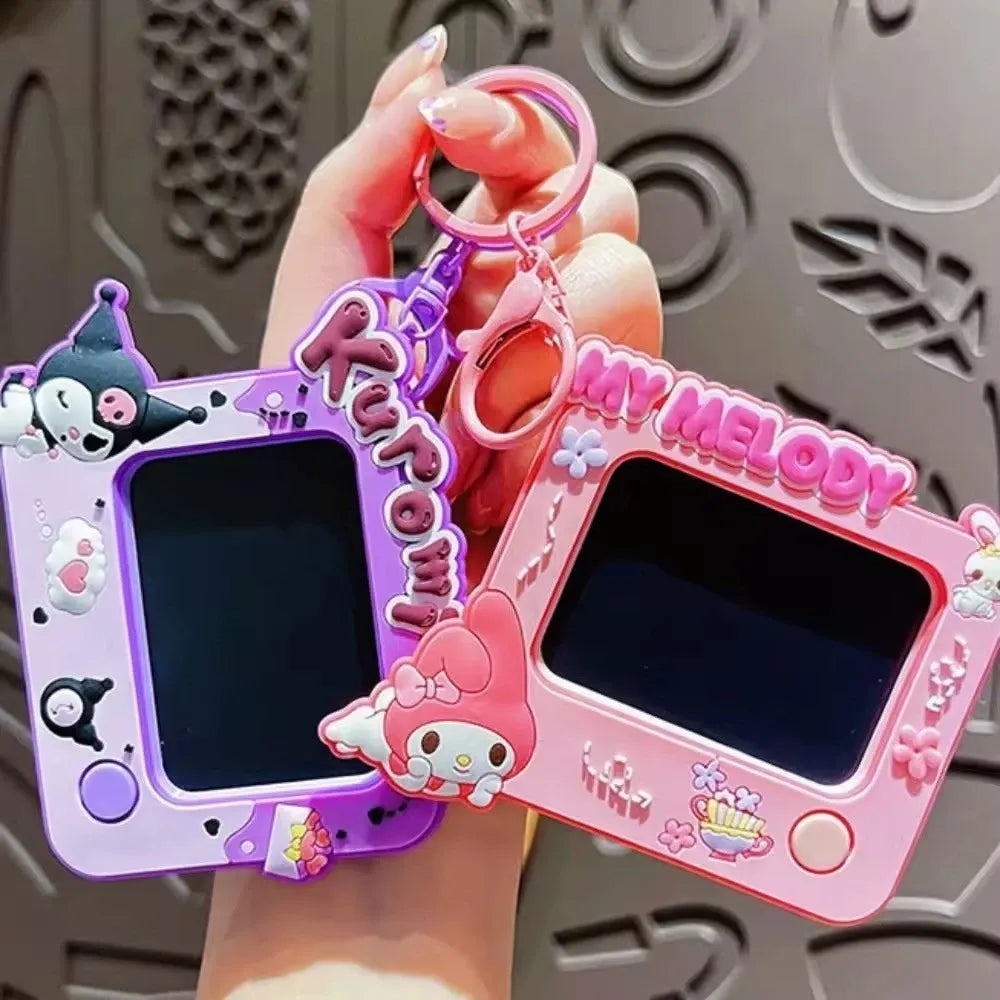 Two 3D cartoon-style handheld digital toy cameras with screens, held in a hand. One is purple with Kuromi and the text 'RUBY MY MELODY', and the other is pink with My Melody and 'MY MELODY' text.