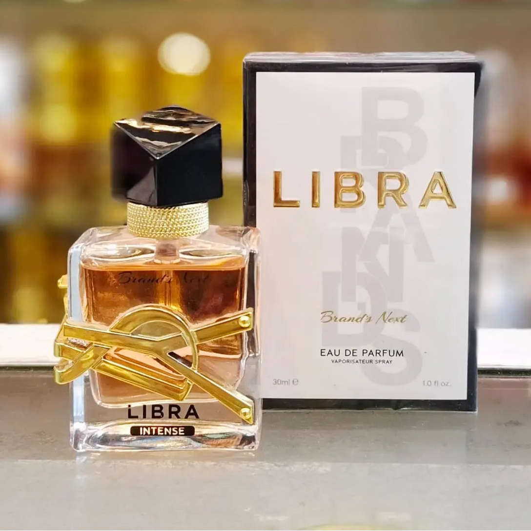 A 30ml bottle of Libra Intense Eau de Parfum with its white and black packaging box, placed on a reflective surface with a blurred perfume shop background. Red text overlay reads 'Brands Next Perfume 30ML'.