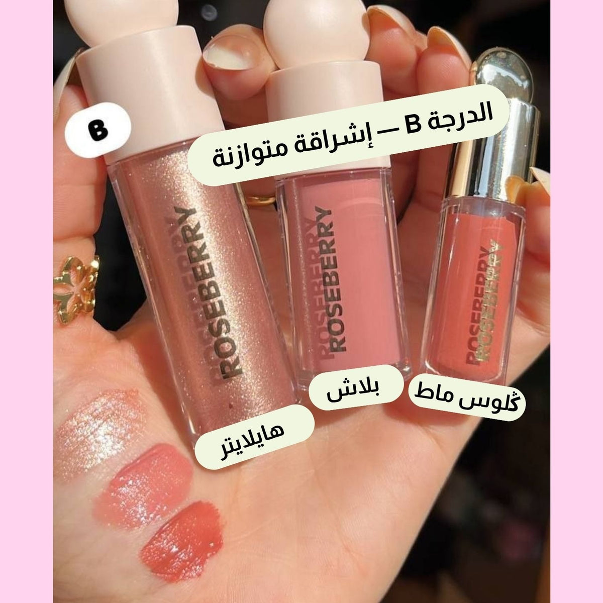 Three Roseberry lip gloss tubes held in a hand, with three corresponding swatches on the palm. Arabic text labels each shade, and the background is pink with a light pink border.