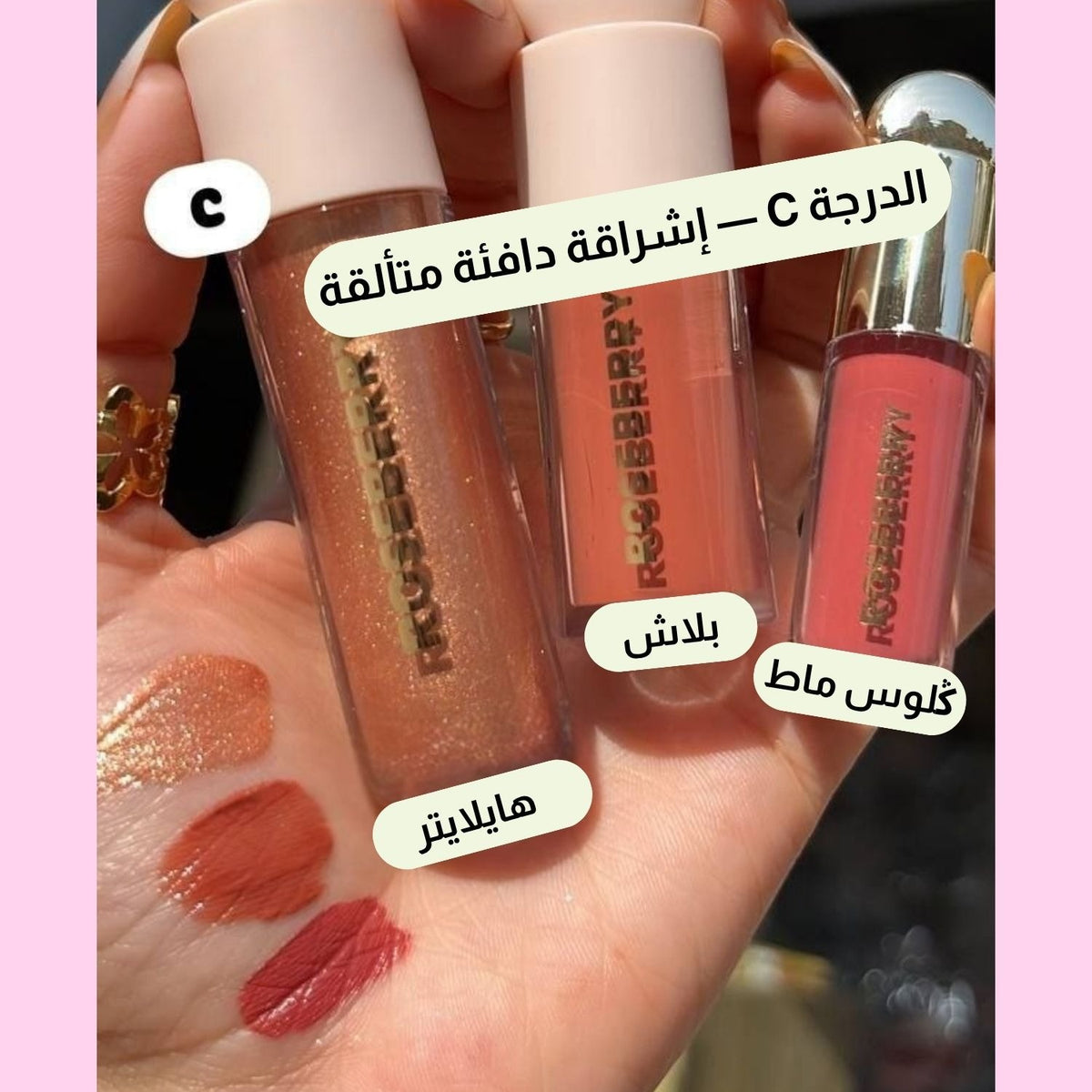 Three Roseberry lip glosses held in a hand, with three corresponding swatches applied on the palm. Arabic text labels each shade, and the image has a pink border.