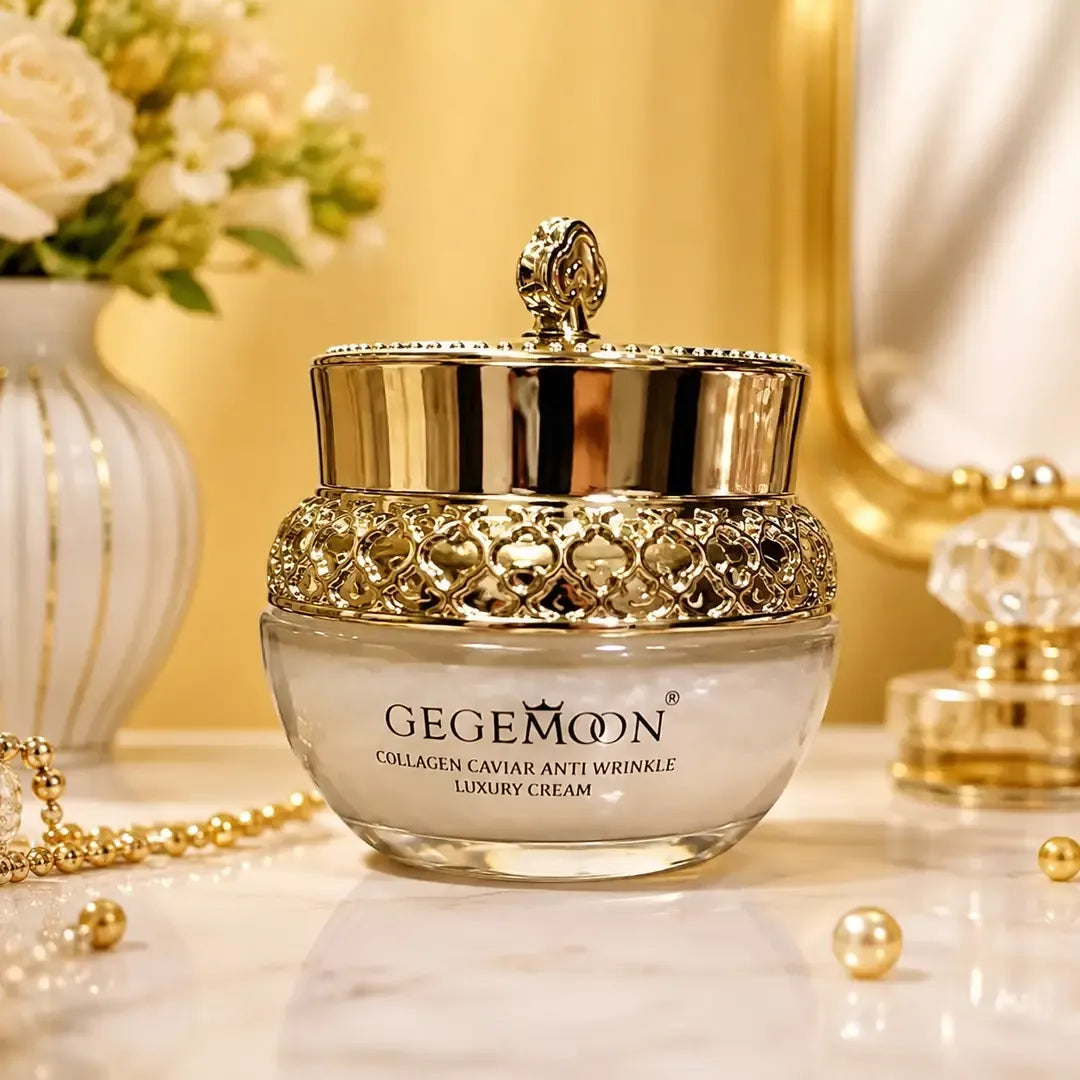 A luxury skincare cream jar by GEGEMOON, featuring a shiny gold lid with a decorative lion emblem and an ornate gold beaded collar. The jar is set on a white marble surface with gold pearls, a gold mirror, and a white flower vase in the background.
