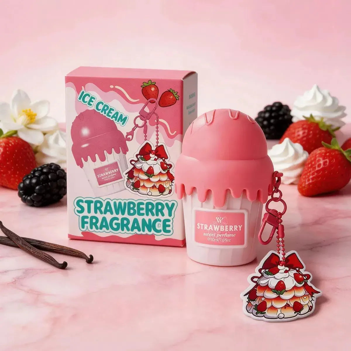 A pink strawberry fragrance product shown with its matching box on a pink marble surface, surrounded by strawberries, blackberries, whipped cream, vanilla beans, and a small matching charm.