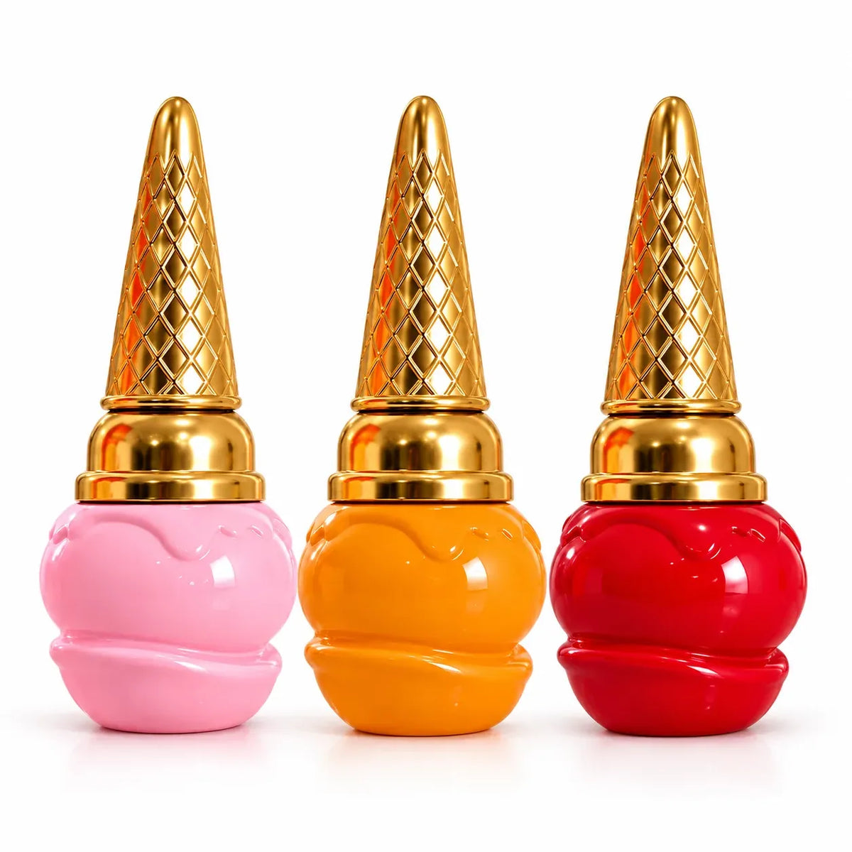 Three glossy, ice-cream-slice-shaped cosmetic containers in pink, orange, and red, each topped with a textured metallic gold cone-shaped cap, arranged side by side on a white background.
