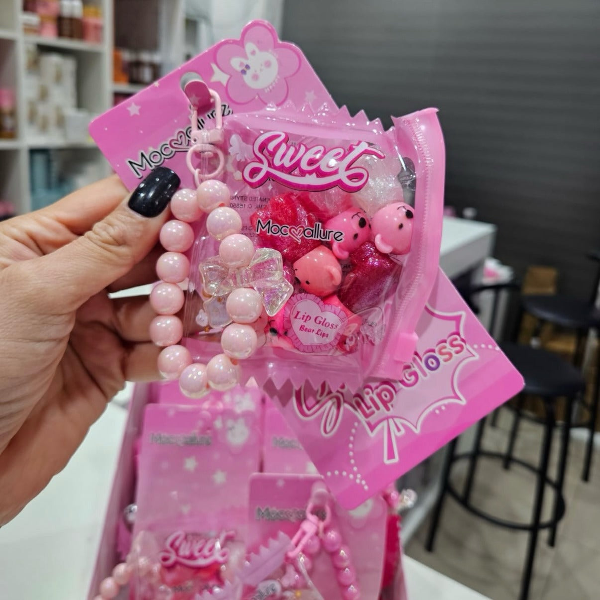 Pink lip gloss set with accessories on a pink packaging in a store setting