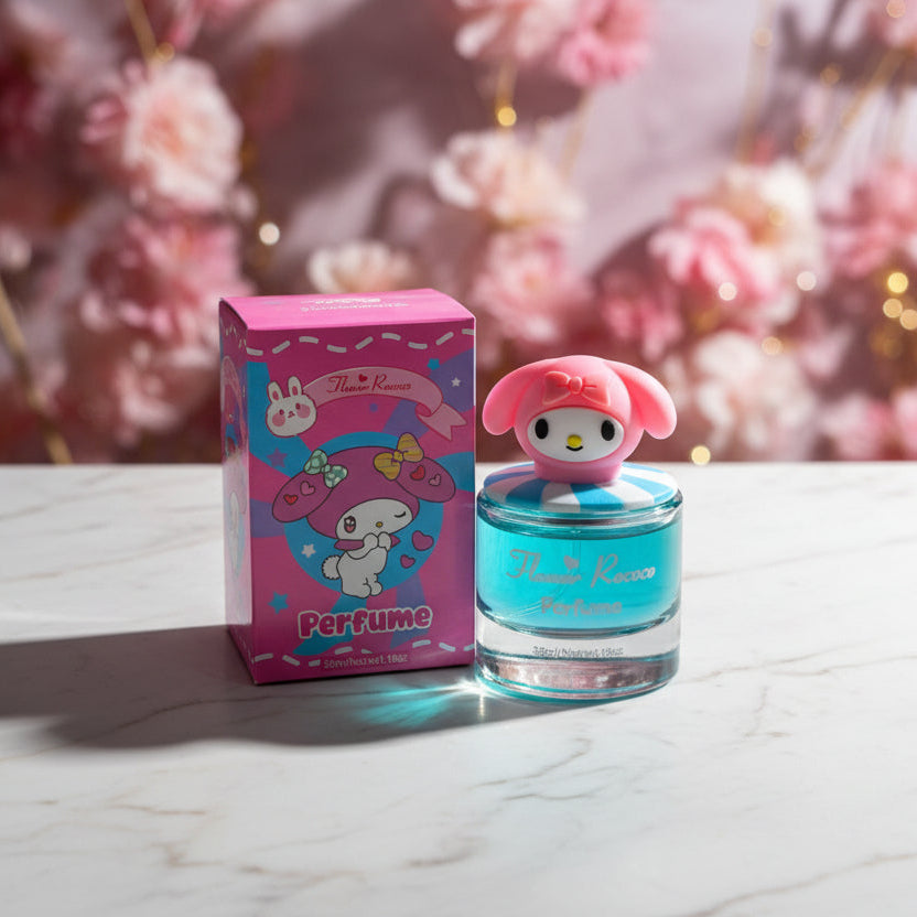 A hand holding a small perfume bottle and its pink retail box in a store setting. The packaging features a cartoon character on a bright pink background, and the bottle has a pink character-shaped cap and a translucent blue-green glass body