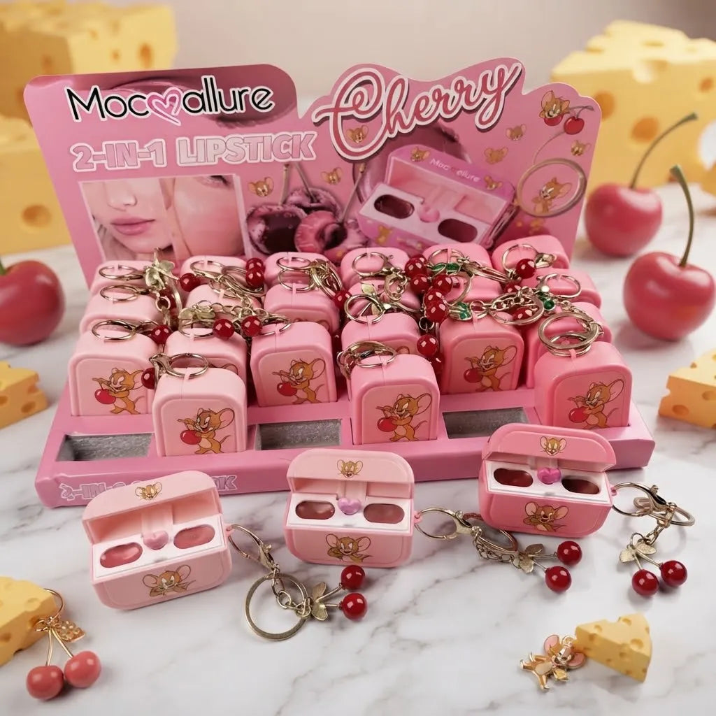 A pink display tray and several loose miniature lipstick cases with cherry-themed charms, including red beads, gold keychains, and small mouse illustrations. The packaging reads 'Mocollure Cherry 2-IN-1 LIPSTICK'.