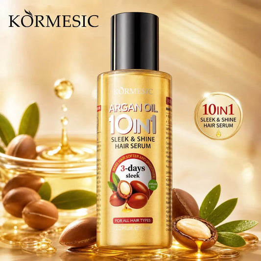 A bottle of Kōrmesic Argan Oil 10in1 Sleek & Shine Hair Serum, presented in a golden bottle with a black cap, surrounded by argan nuts, leaves, and golden oil droplets on a warm gold background.