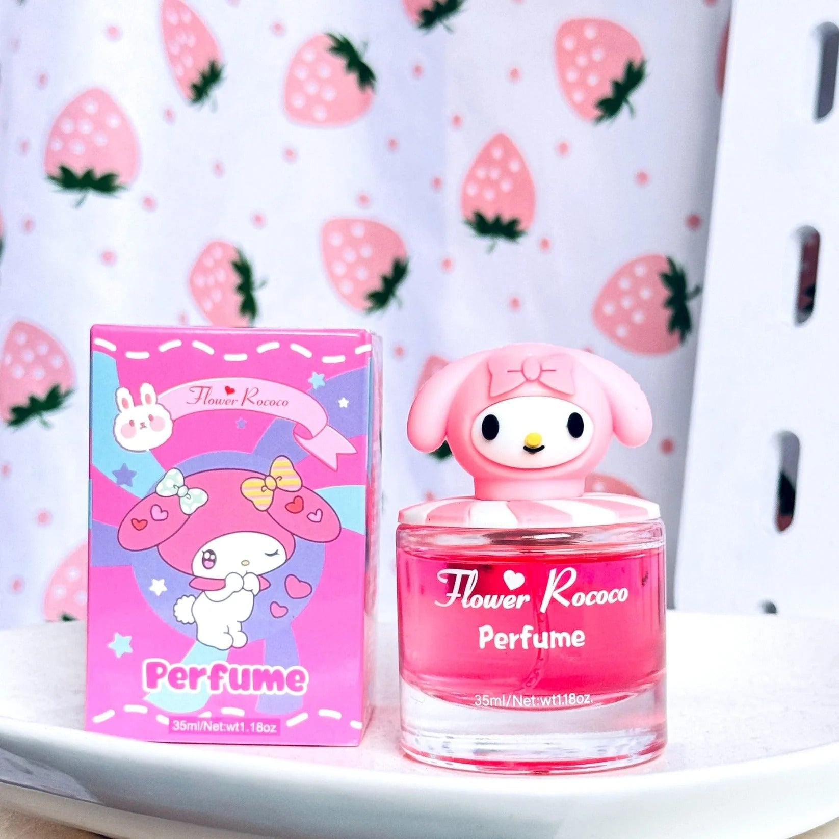 Flower Rococo Perfume bottle and its pink retail box featuring a cartoon rabbit character, set against a strawberry-patterned backdrop.