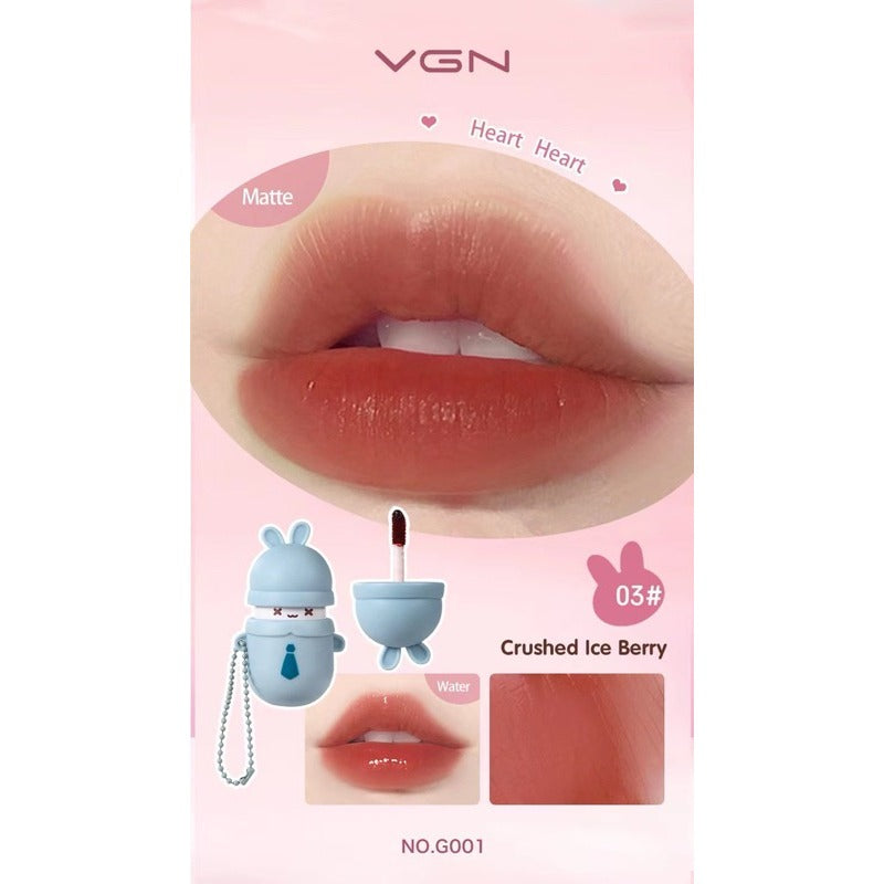 VGN matte lip gloss packaging in shade Crushed Ice Berry (03#). The pink card features a large close-up of lips wearing the glossy peachy-pink lip color, along with illustrations of the light blue bunny-shaped lip gloss container and applicator, and a small product swatch.