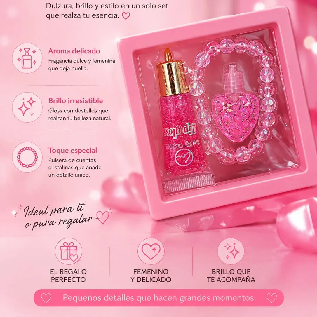 Pink gift set featuring a glittery pink perfume bottle with a gold cap, a matching pink beaded bracelet, and a small clear bottle with a pink heart-shaped charm, presented in a pink box with Spanish promotional text.