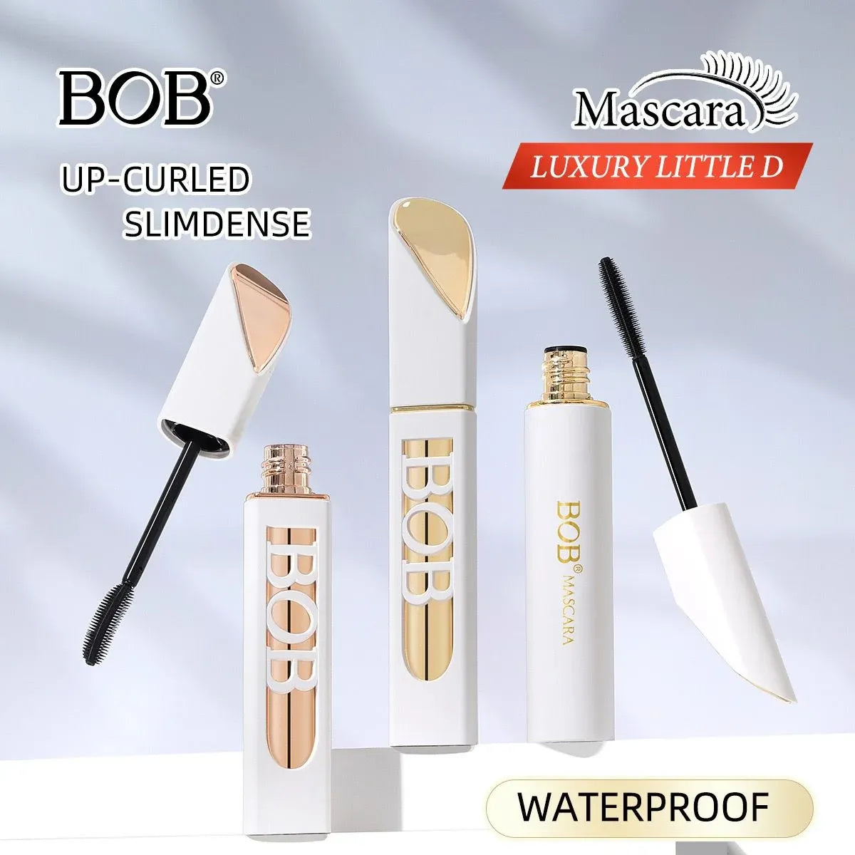 BOB Up-Curled Slimdense Mascara in white and gold packaging, shown with the wand uncapped and the brush visible, on a light gray background with text overlays including 'Mascara', 'LUXURY LITTLE D', and 'WATERPROOF'.
