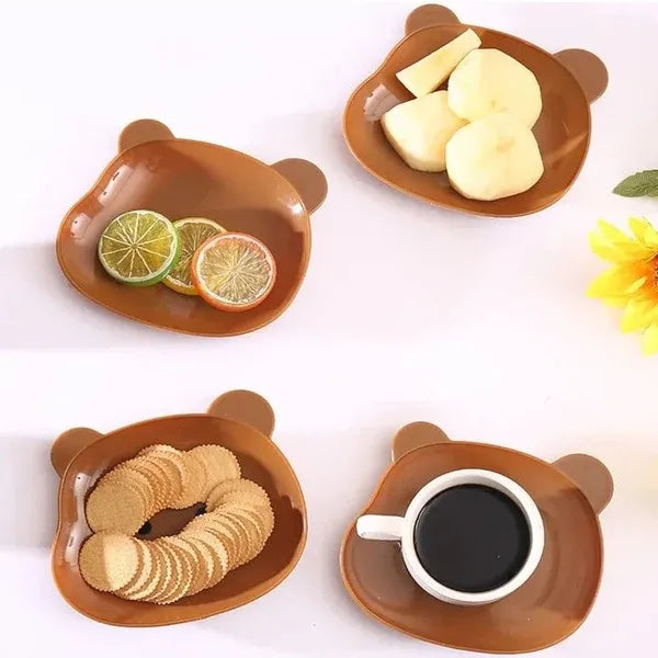 Four bear-shaped ceramic plates with different food items on a white background
