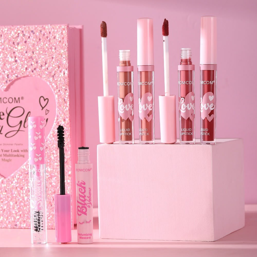 Six pink-toned beauty products from NICOOM, including lip glosses and a mascara, arranged on and around a pink display block with a glittery pink box in the background.