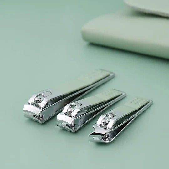 Set of three silver nail clippers on a light green background