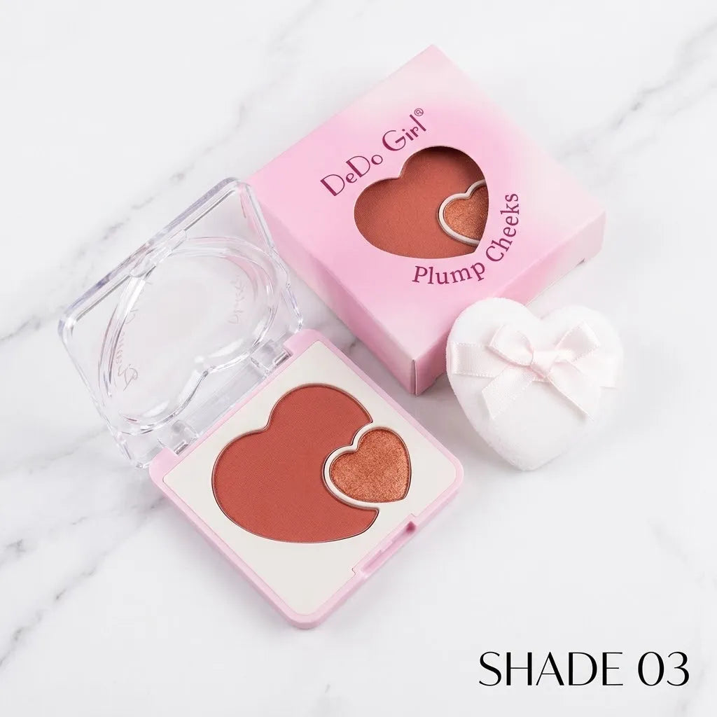 A heart-shaped blush compact by DaDo Girl in shade 03, shown open with the pressed powder and its pink packaging box on a white marble background.