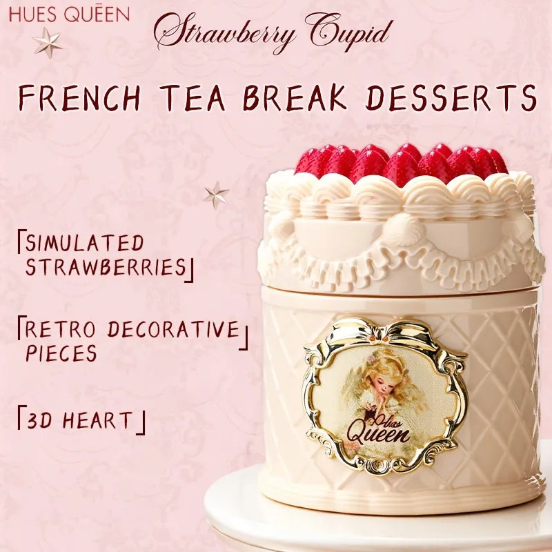 A decorative dessert tin styled like a cream-colored cake with piped strawberry frosting on top, shown on a pink background with promotional text reading 'HUES QUEEN Strawberry Cupid FRENCH TEA BREAK DESSERTS' and feature callouts.