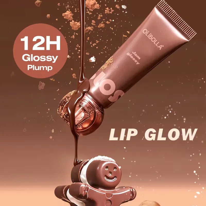A tube of OLBOLLA lip gloss in the 'Jelly Dreamery' shade is shown dripping glossy brown lip product onto a gingerbread figure and a heart-shaped heart candy, with a '12H Glossy Plump' badge on a warm brown background.