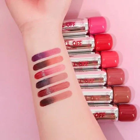 Set of lip glosses with swatches on a hand against a pink background